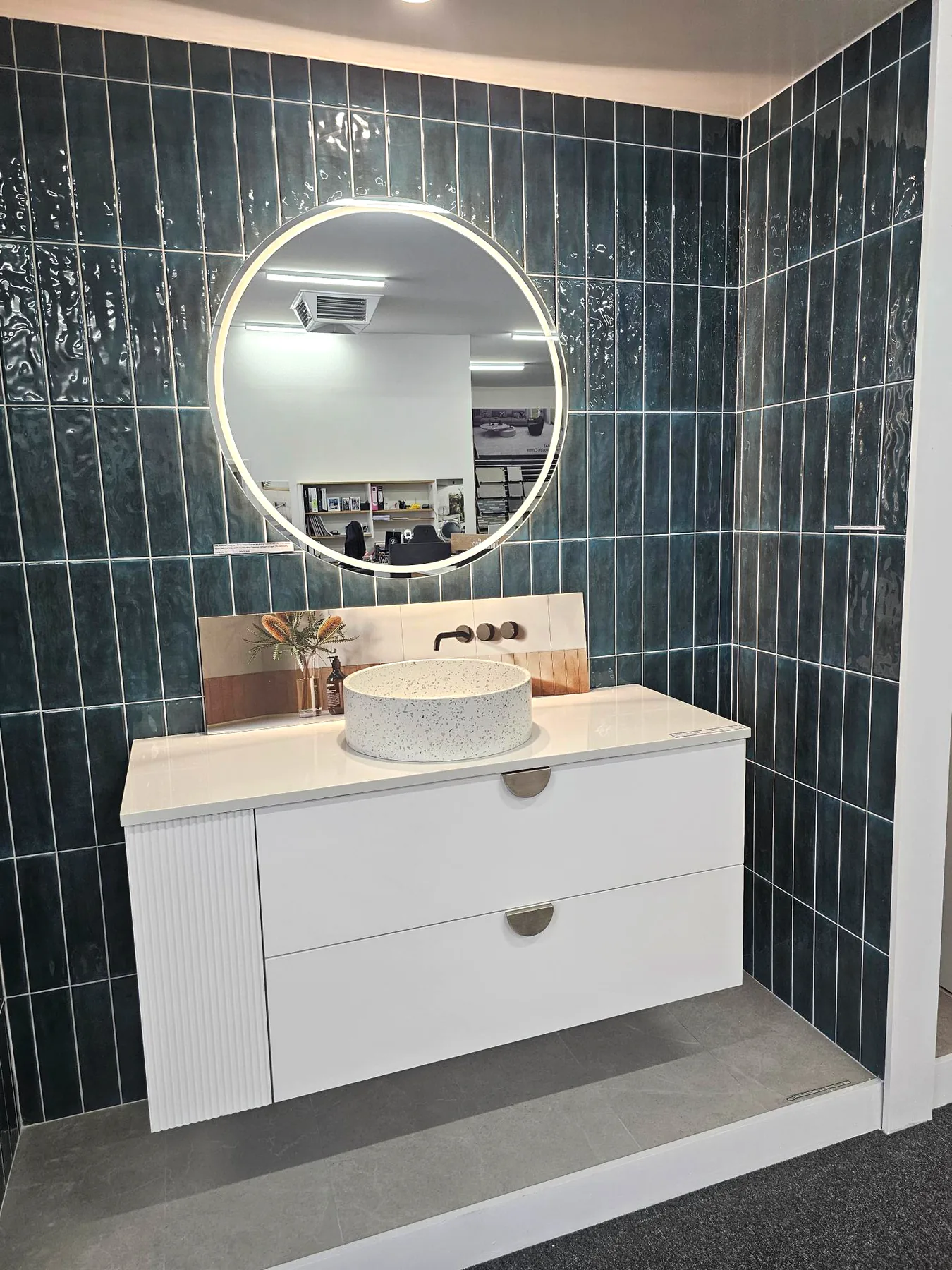 A white vanity with a fluted end and a terrazzo vessel basin