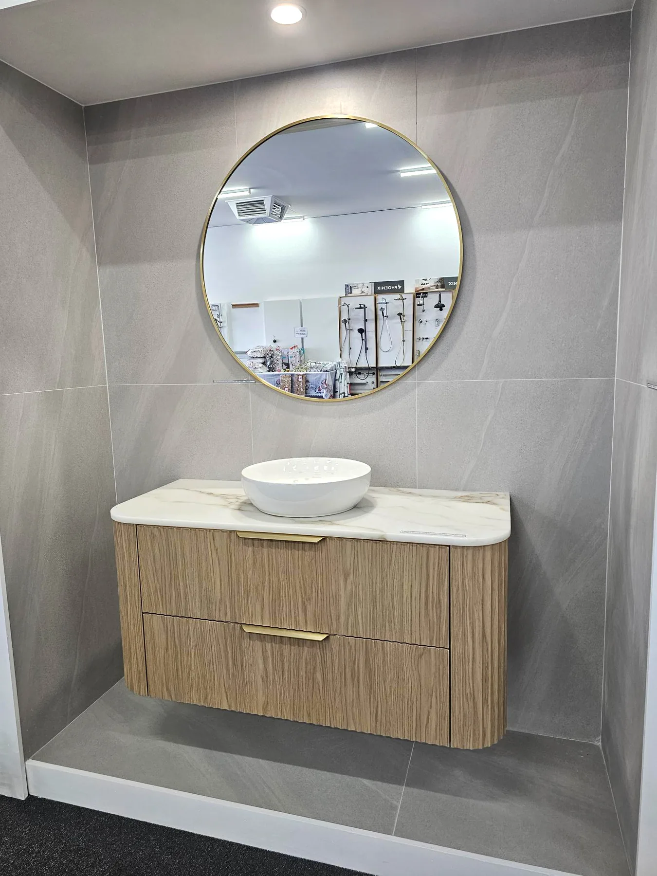Light oak curved wall hung vanity, marble look top, round vessel basin and gold framed mirror