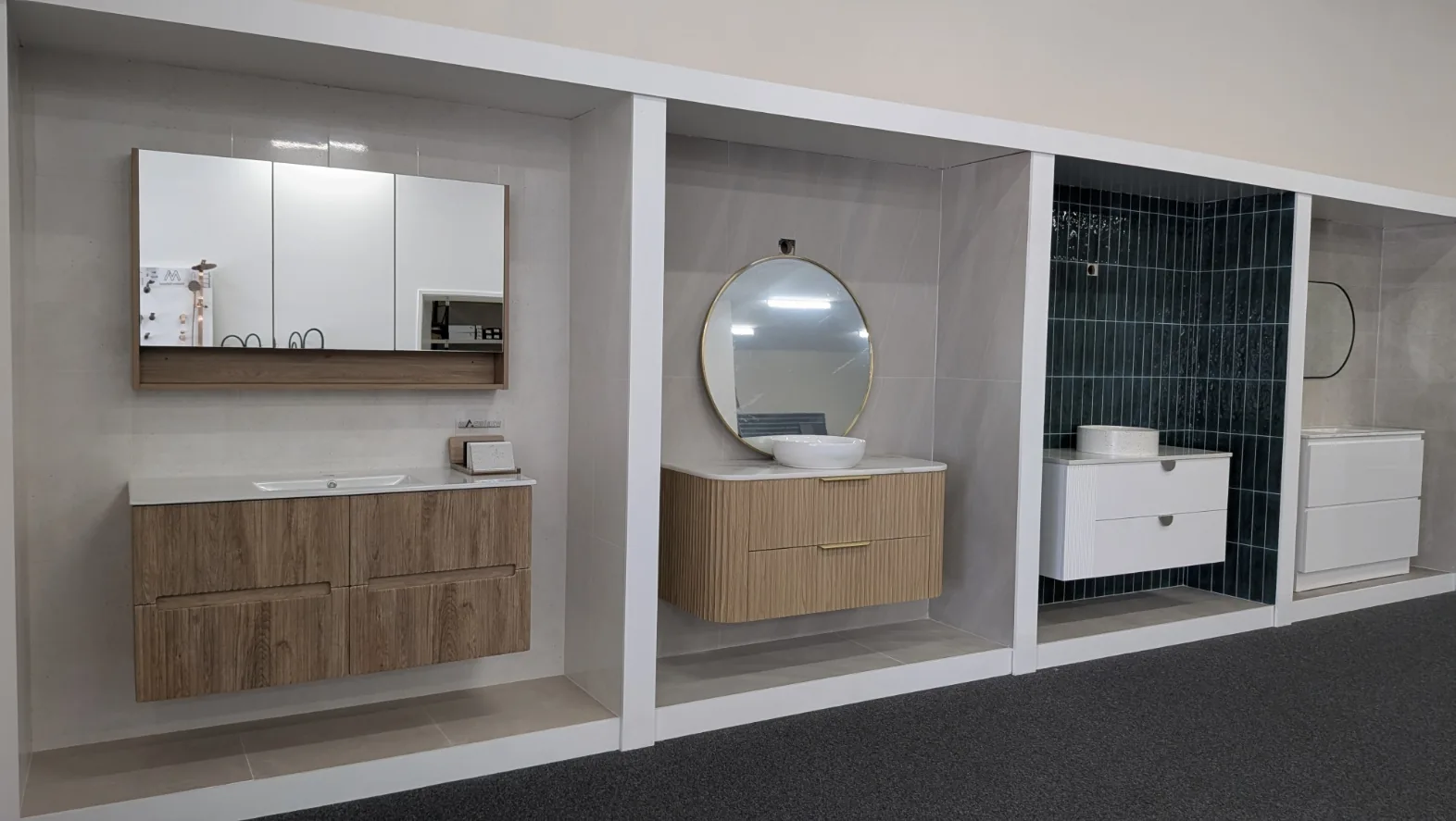 Three styled display bays at the Osborne Park showroom with shaving cabinets, timber and white vanities and round mirrors