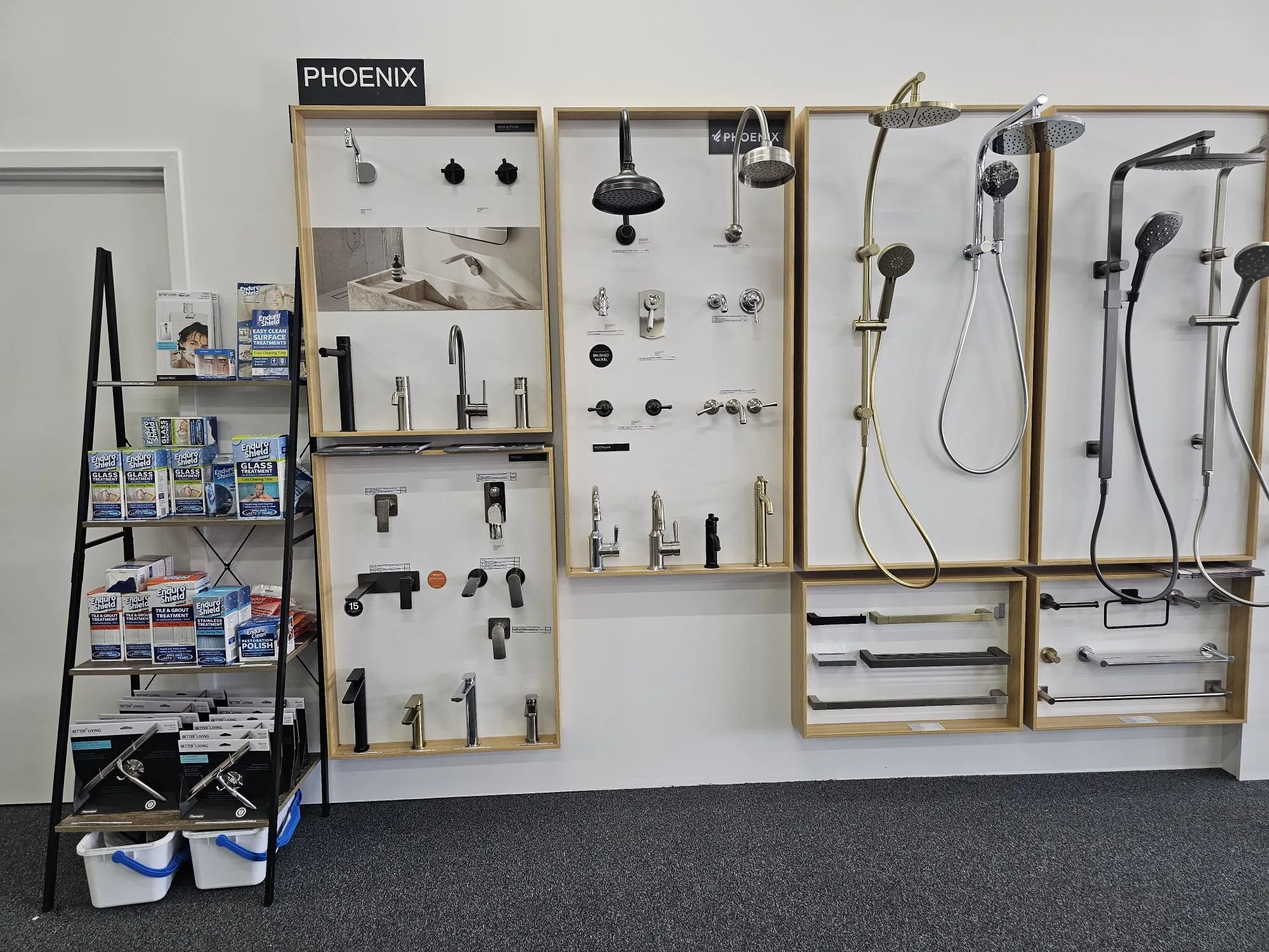 Phoenix Tapware display wall at the Osborne Park showroom, showing mixers, shower rails and handpieces in matte black, chrome and brushed finishes