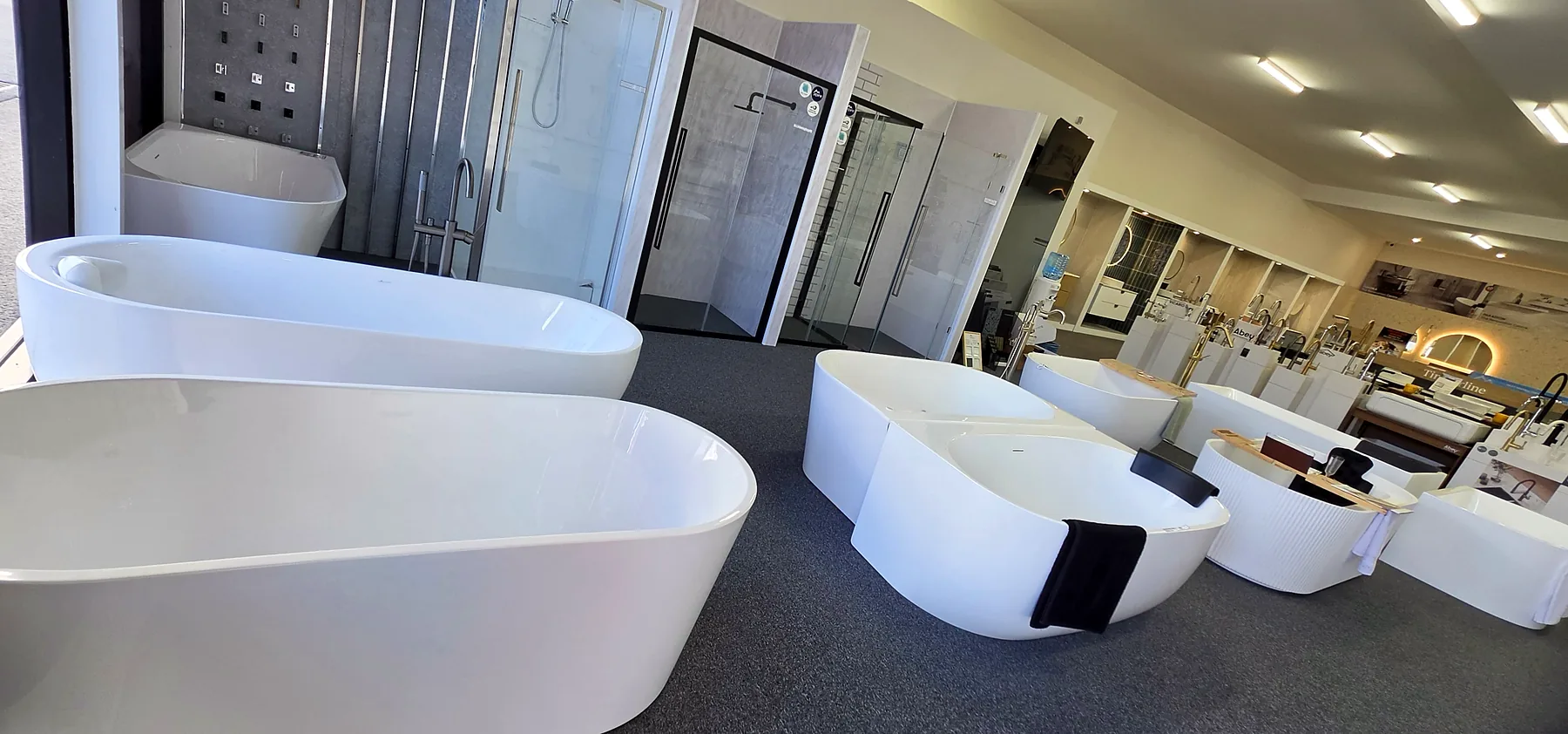 Freestanding baths lined along the Osborne Park showroom floor beside the shower screen displays