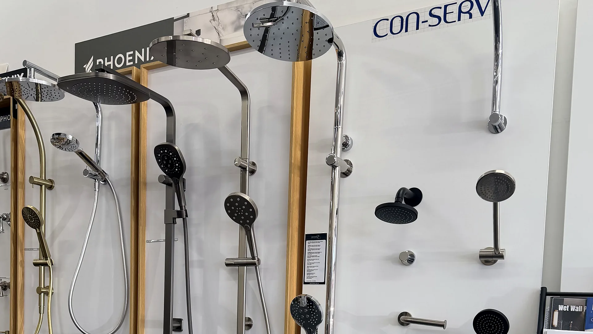 Con-Serv display panel in the Osborne Park showroom with chrome rain showers, hand showers on rails and matte black wall outlets