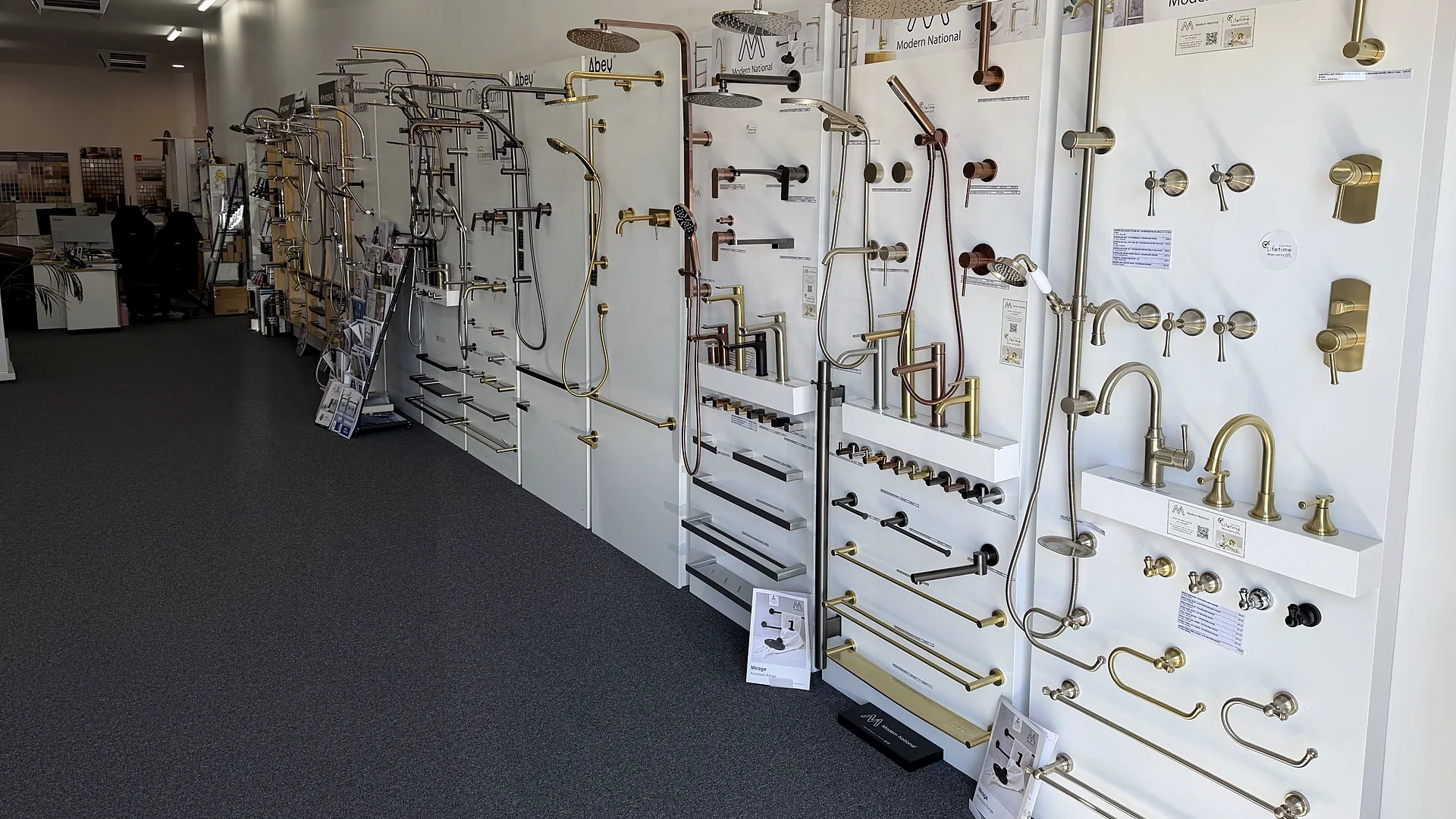 Modern National display wall of basin and sink mixers, rail showers and towel rails in brushed brass, copper, chrome and matte black