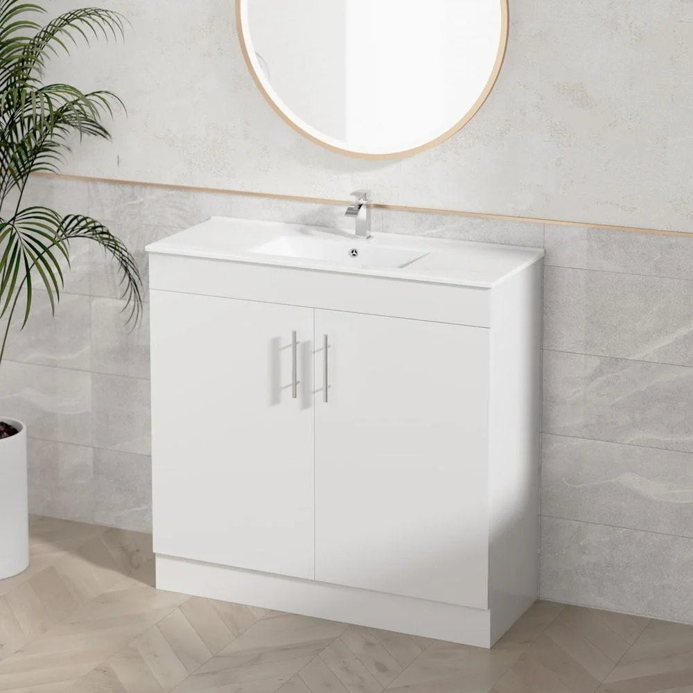 Jessica 900mm gloss white floor standing vanity with two doors, chrome bar handles and a moulded ceramic basin top, styled against stone look tiles with a round timber mirror