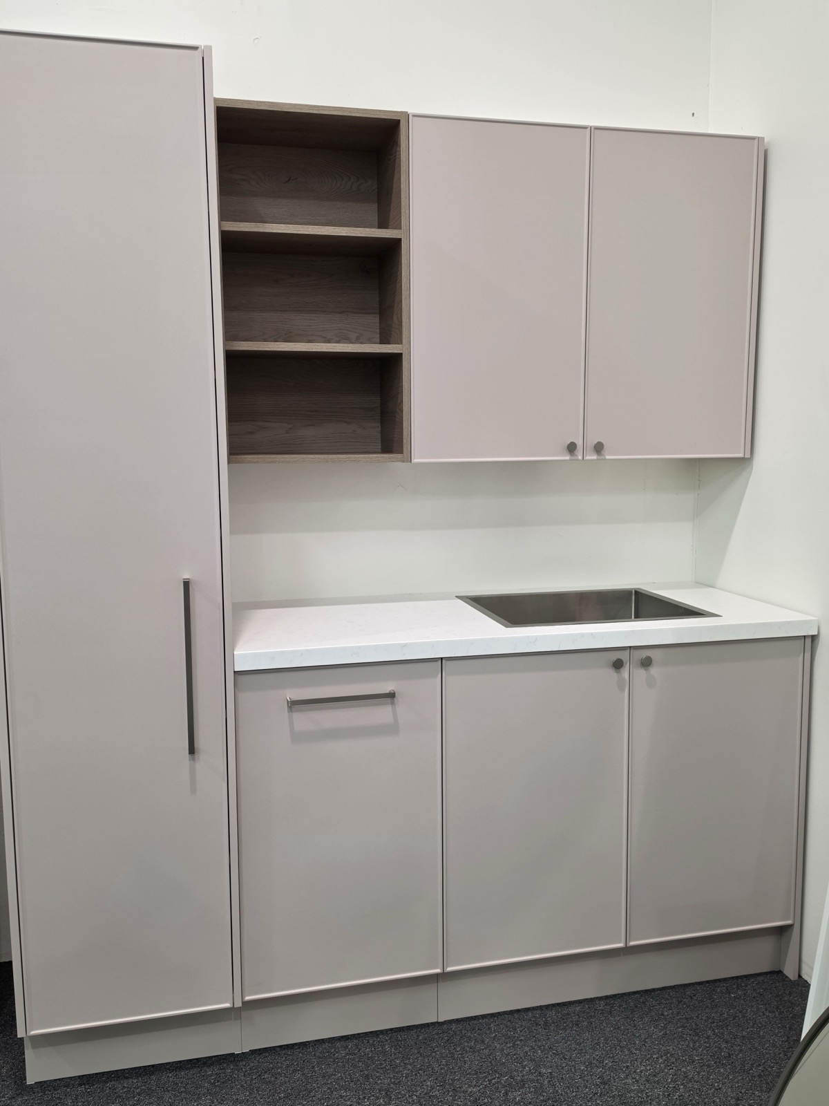 Custom Timberline laundry on display in the Osborne Park showroom in a soft blush finish, with open oak shelving, a stone benchtop, a stainless sink and a full height cupboard