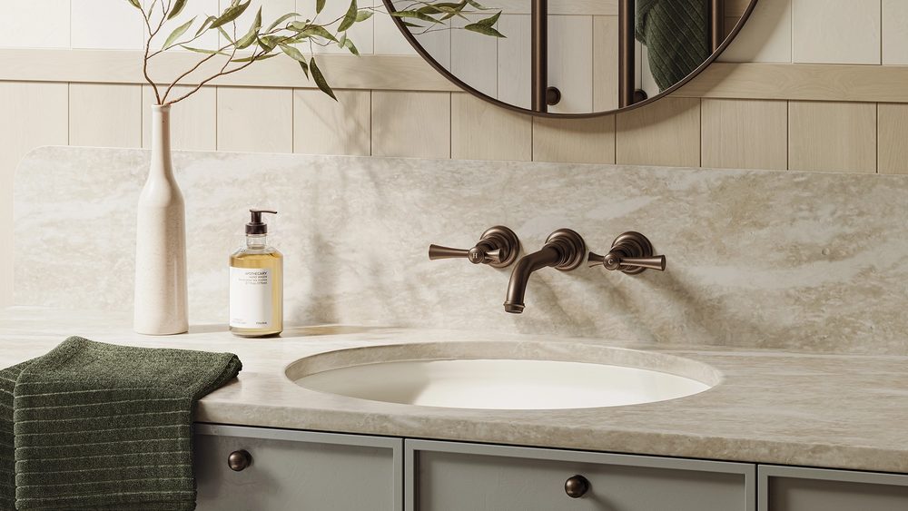 Phoenix Cromford wall tapware in aged brass above a stone basin with a round mirror