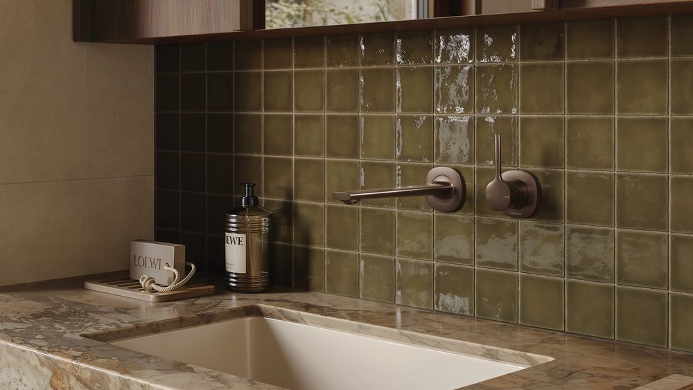 Phoenix Vask wall outlet above an undermount basin on a green tiled wall