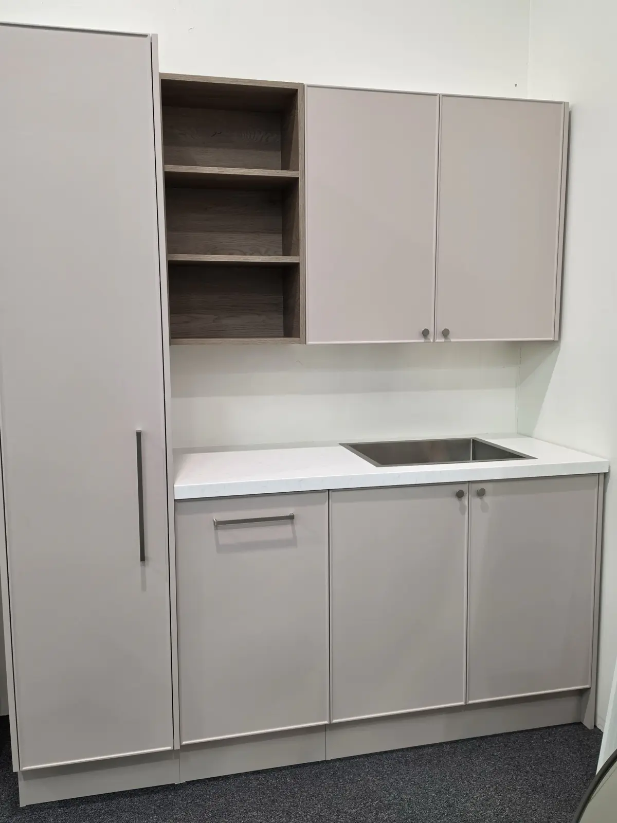 Custom Timberline laundry on display in the Osborne Park showroom in a soft blush finish, with open oak shelving, a stone benchtop, a stainless sink and a full height cupboard