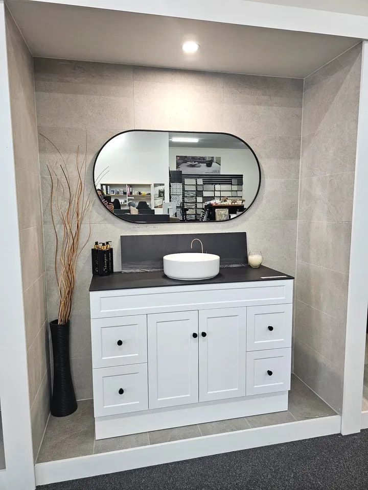 White shaker vanity, black stone top and splashback, round vessel basin and black framed oval mirror, in the Alpine display pod