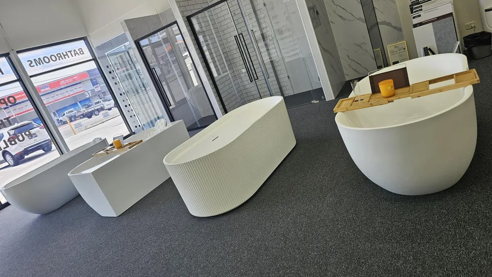 Freestanding baths on display along the front of the Osborne Park showroom, with shower screens behind them