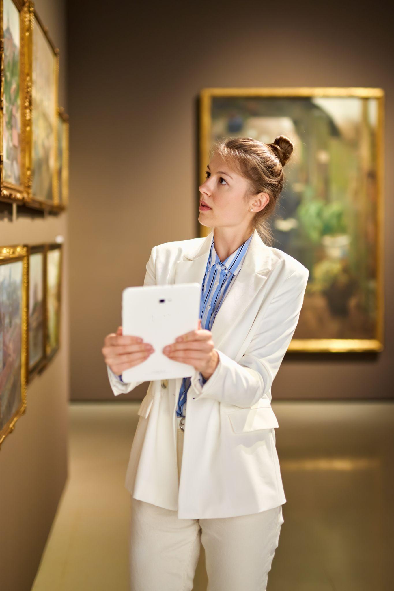 Art student reviewing works in a gallery with a tablet