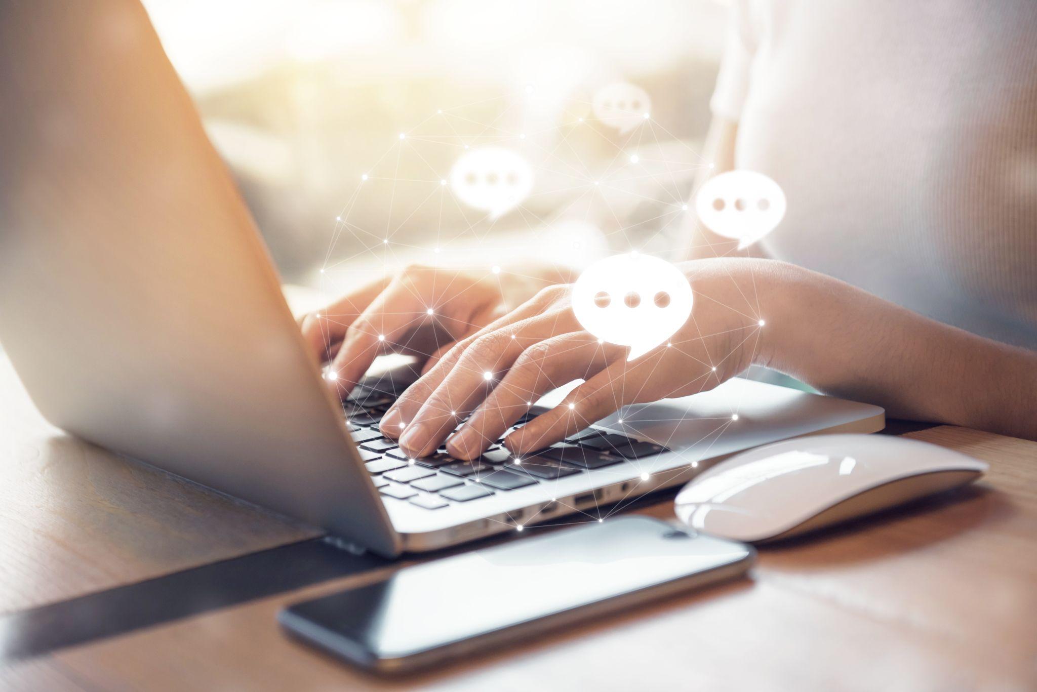 Hands typing on a laptop with chat bubbles representing in-video discussion