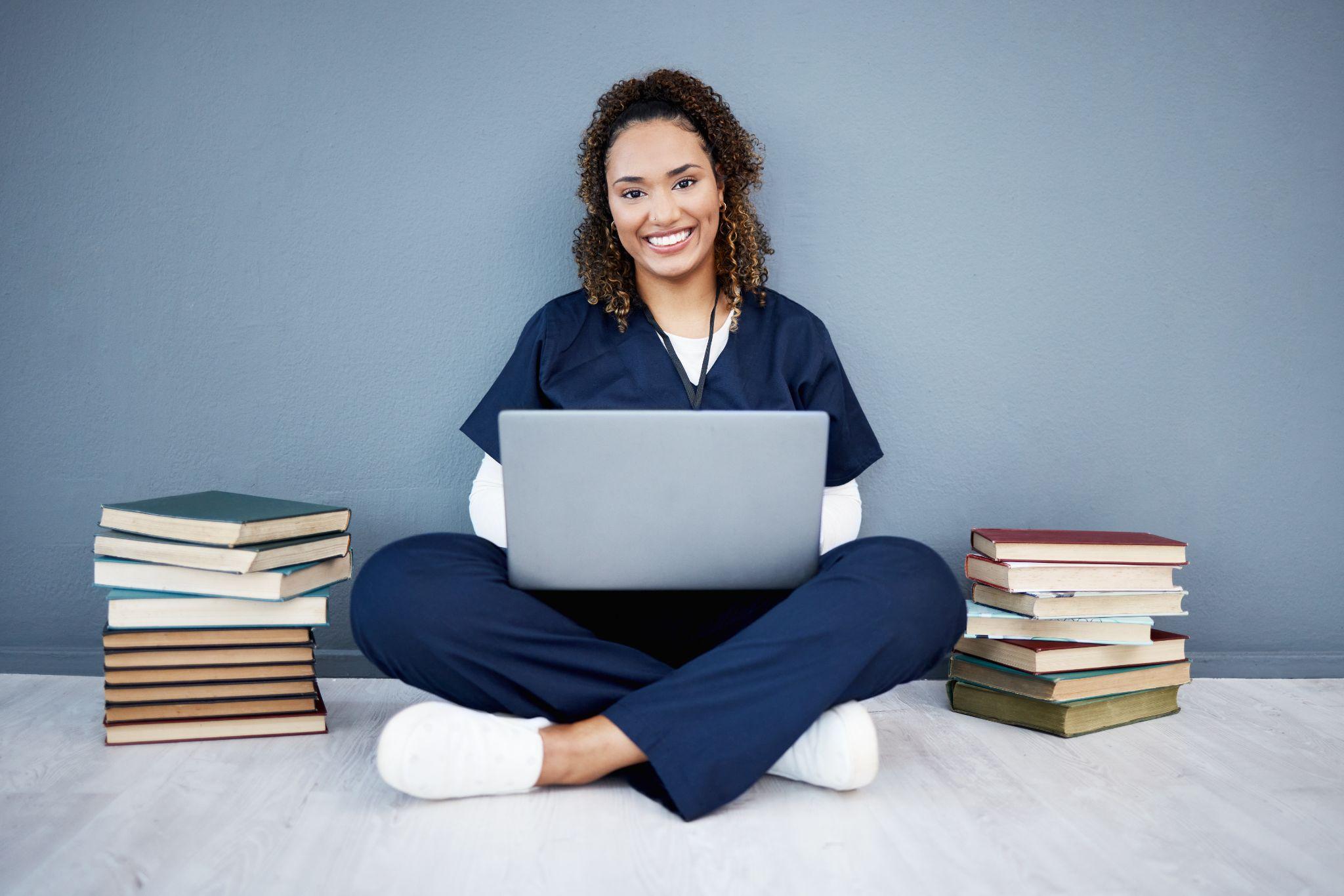 Pharmacy student learning with a laptop and stacks of books