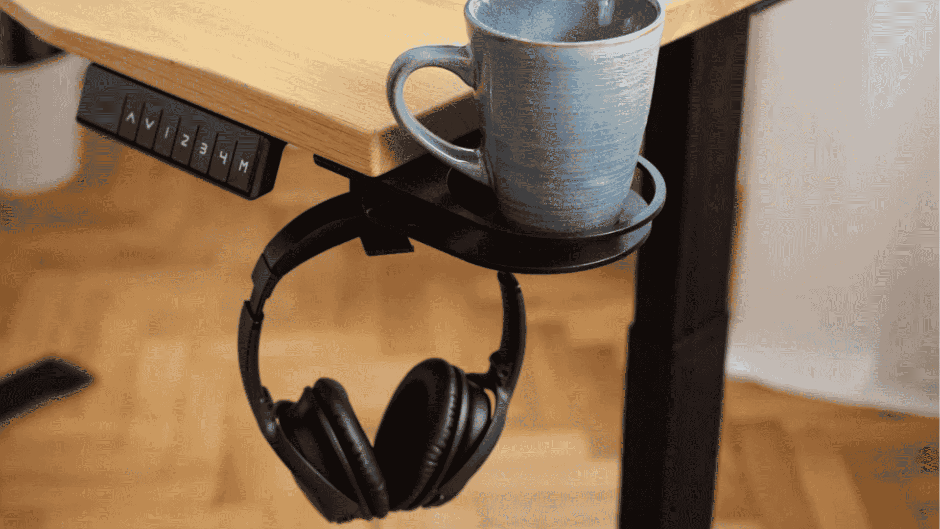 ErgoHide under-desk cup holder shown with a mug and headphones