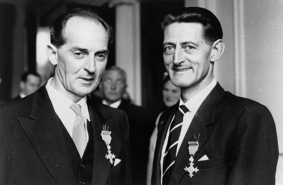 Two men in suits wearing medals, standing side by side and facing the camera in a black and white photo.