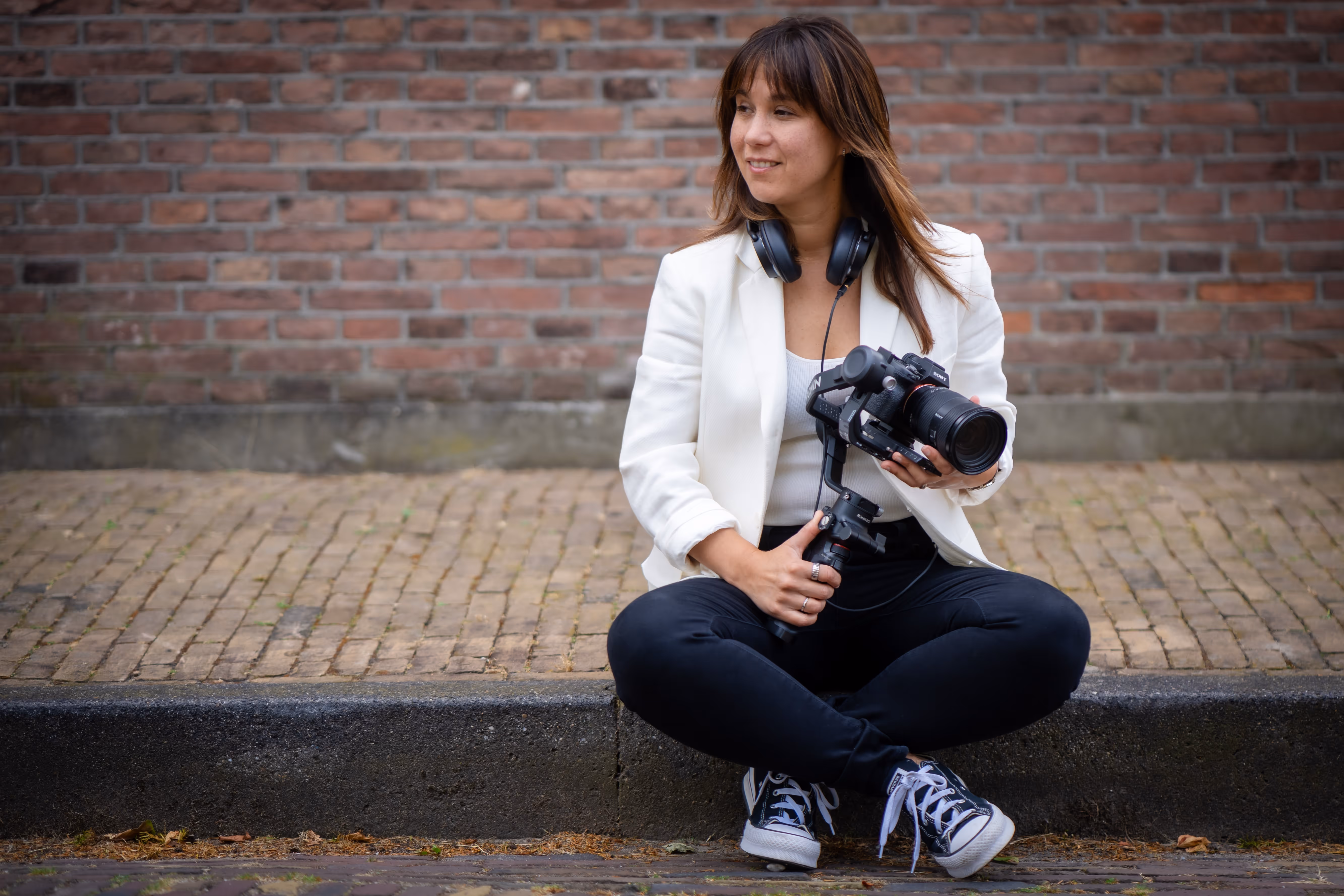 Lois Nieuwenhoven zit op een stoep met haar camera en koptelefoon.