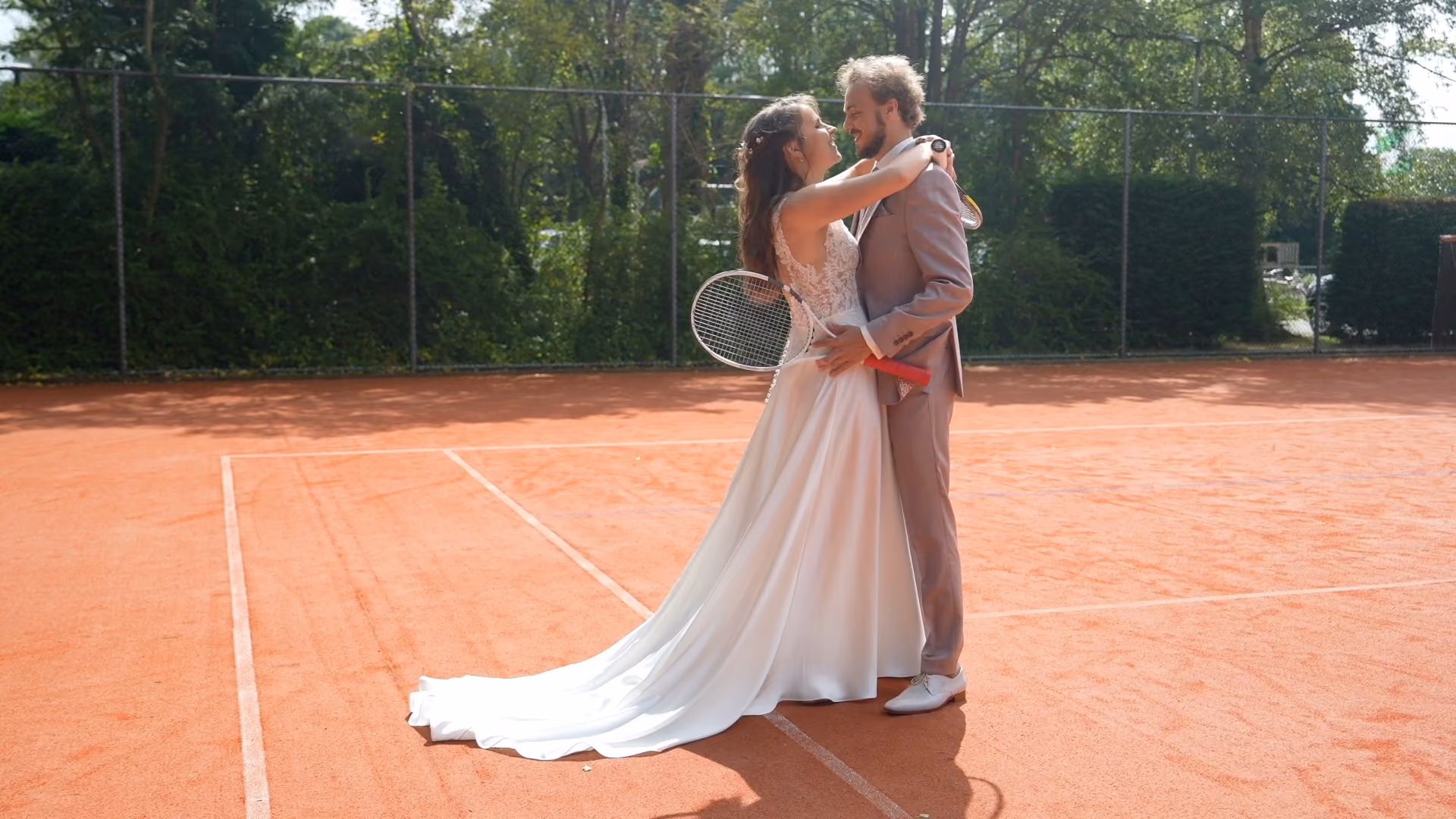 Bruidspaar kust op een tennisbaan.
