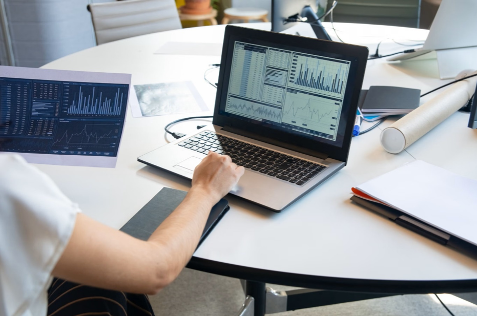A data analyst examining complex charts and data visualisations on a laptop screen for public sector data recruitment.