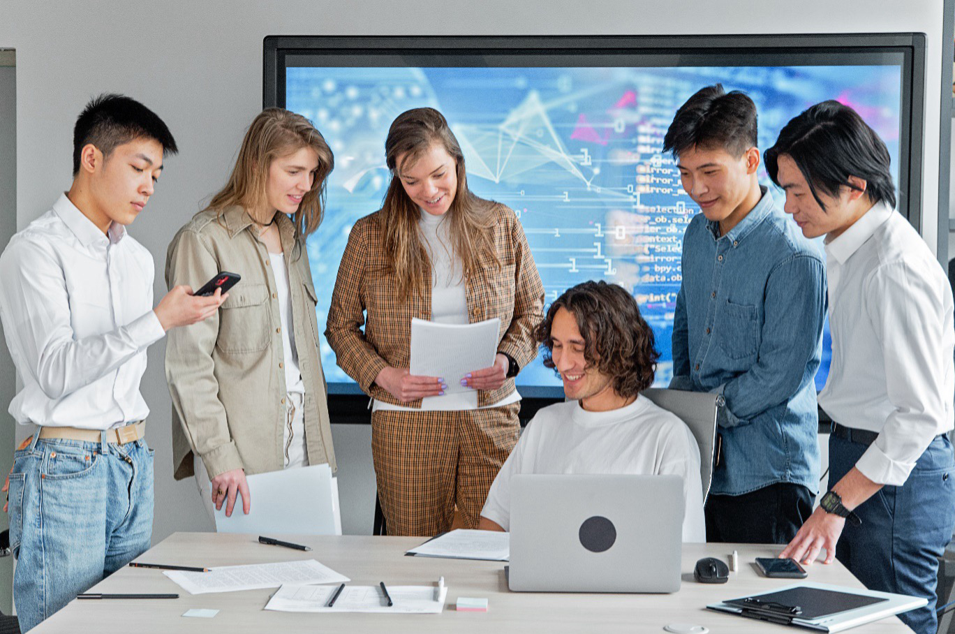 : A modern multidisciplinary team conducting a digital strategy session around a laptop in a public sector office.