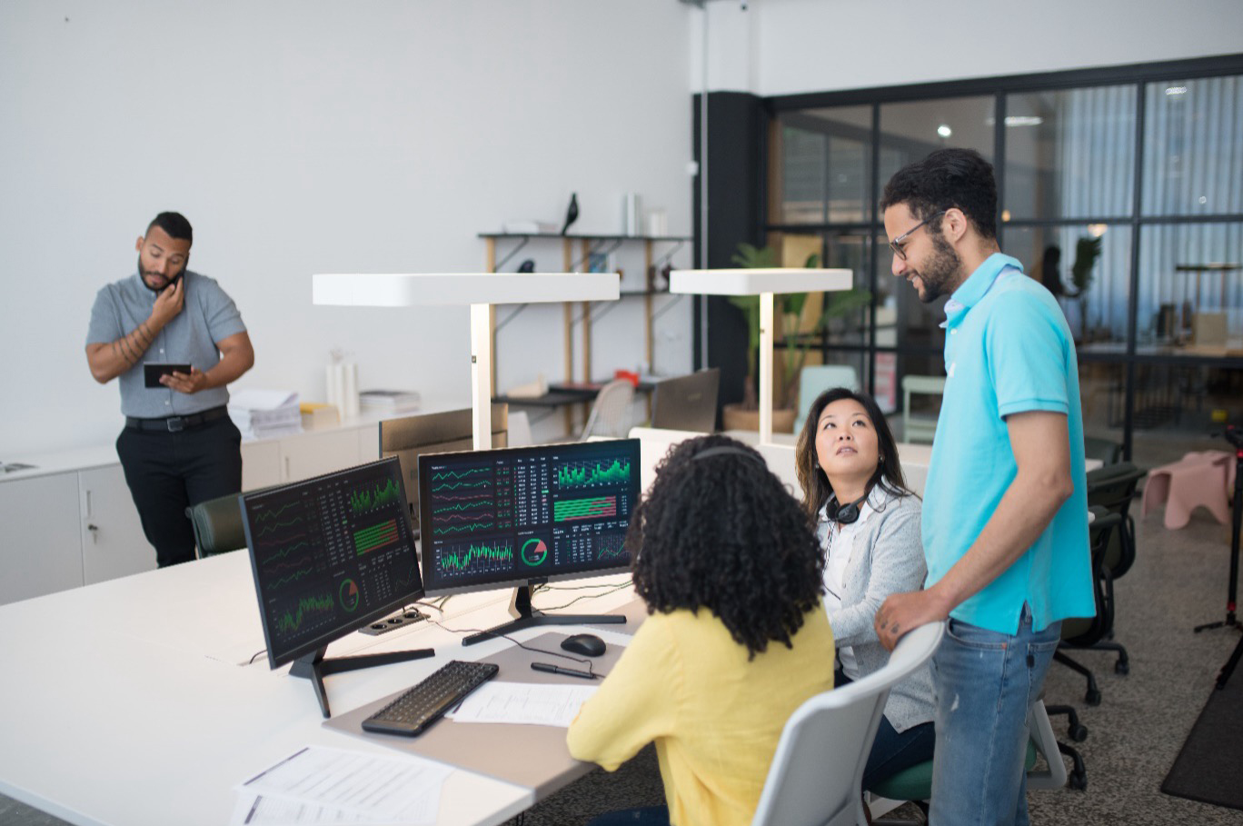 A diverse multidisciplinary team collaborating on digital service analytics in a modern office.
