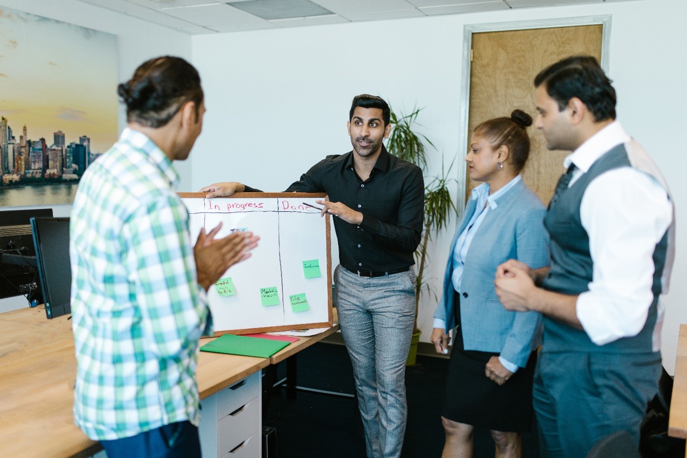 A public sector delivery team reviewing user stories and continuous testing progress around a sprint board during a stand-up.
