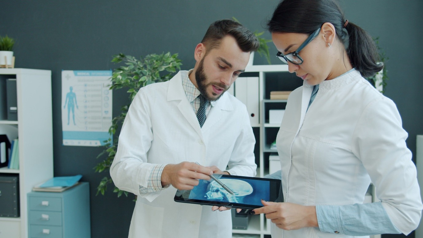 Two medical specialists reviewing digital imaging on a tablet using AI in healthcare diagnostic tools.