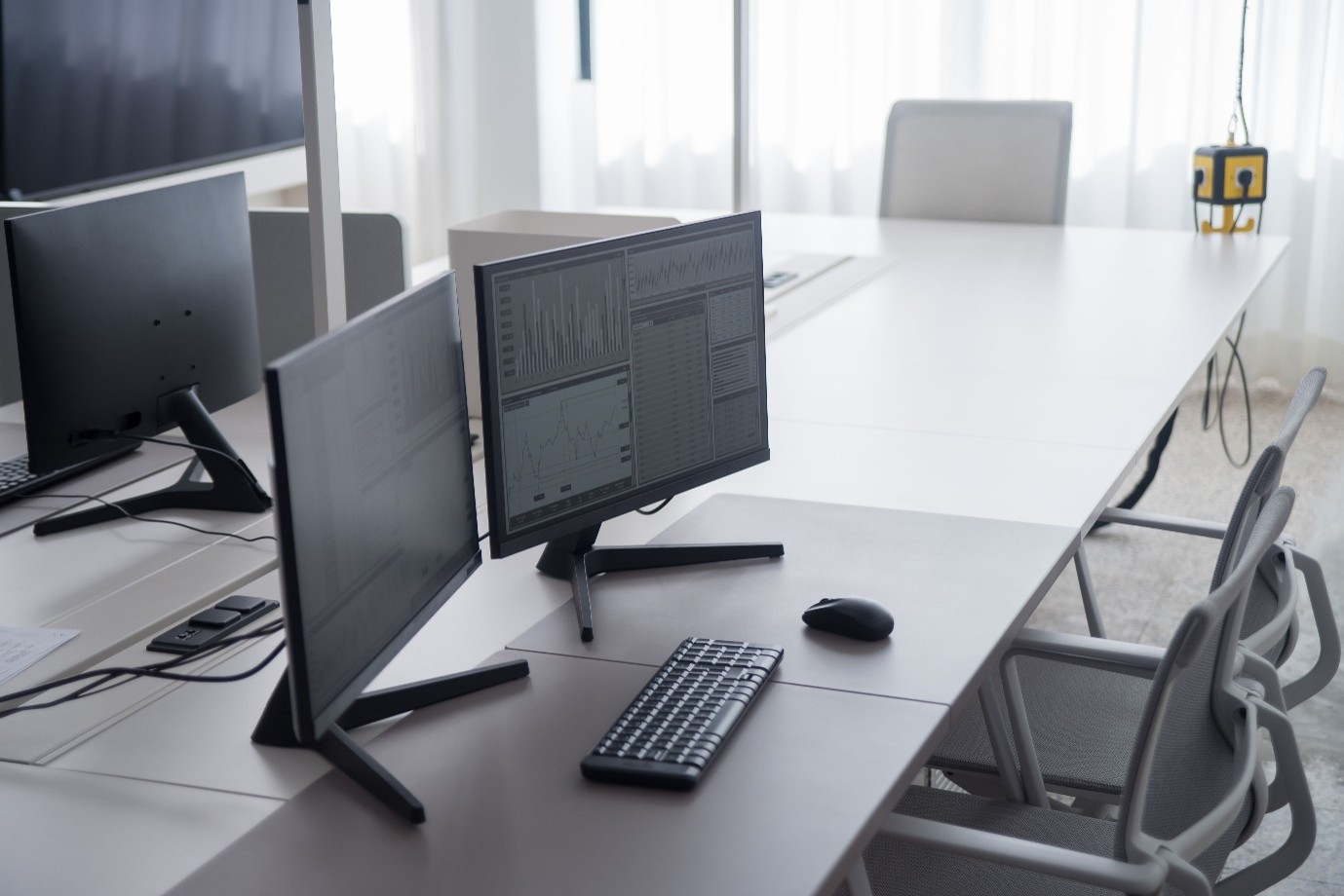 Desktop monitors showing data analytics dashboards and central reporting interfaces mandated under procurement law.