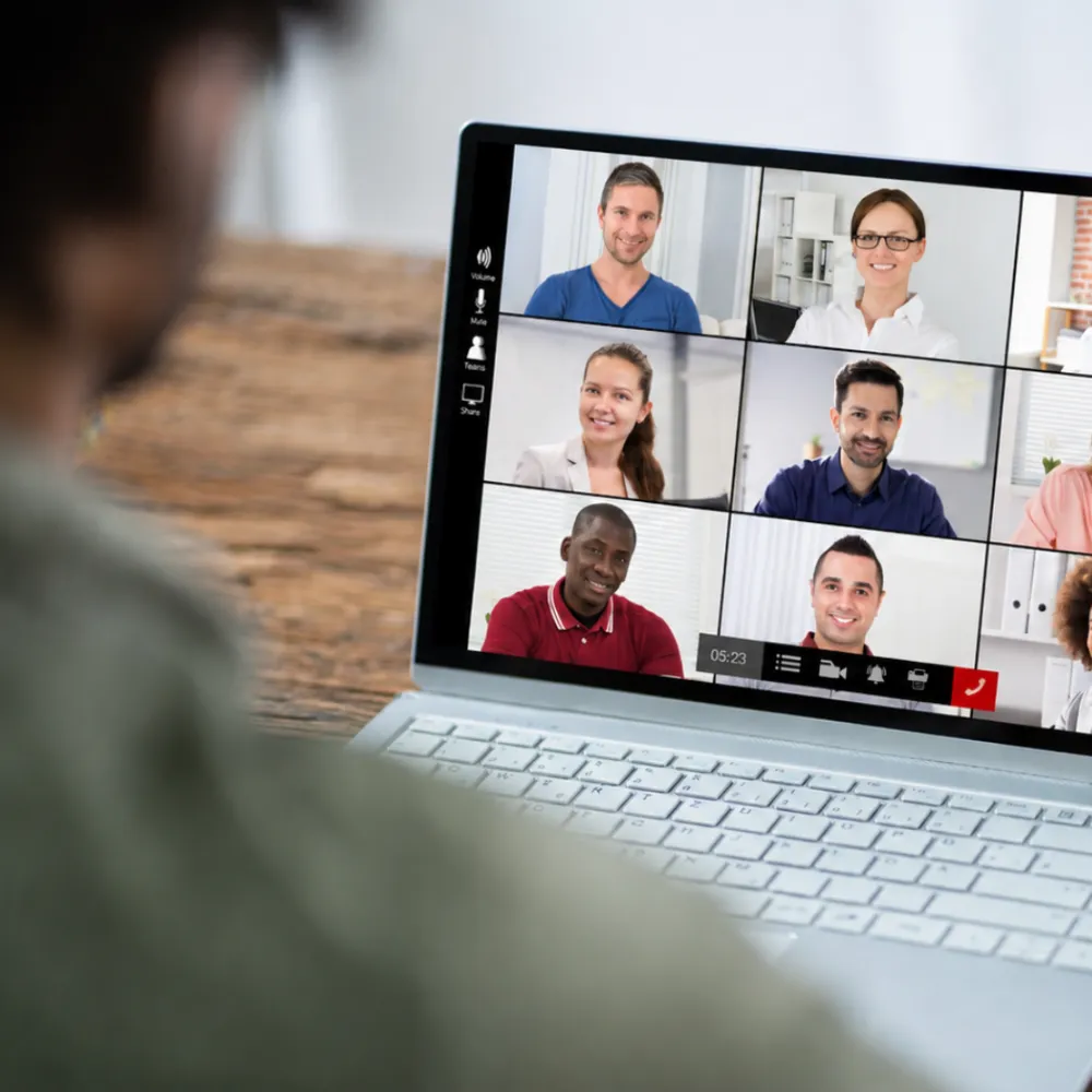 Personne participant à une visioconférence avec six collègues affichés sur l'écran d'un ordinateur portable.