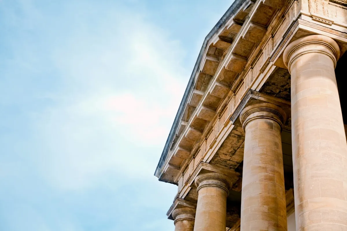 Façade avec colonnes massives de style classique et ciel bleu clair en arrière-plan.