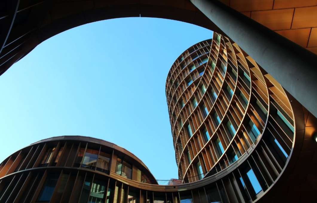 Immeubles modernes en forme incurvée avec grandes fenêtres sous ciel bleu clair.