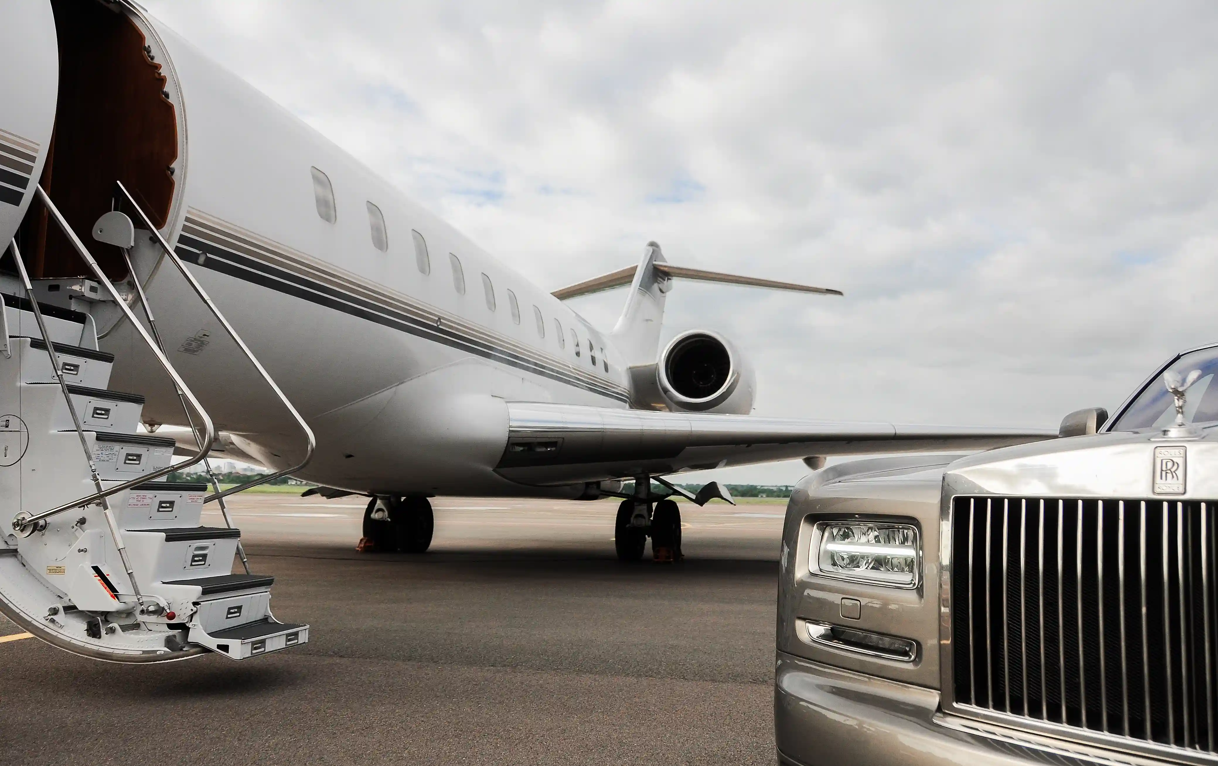 Privatjet auf dem Rollfeld mit ausgefahrener Treppe neben einer luxuriösen Limousine.