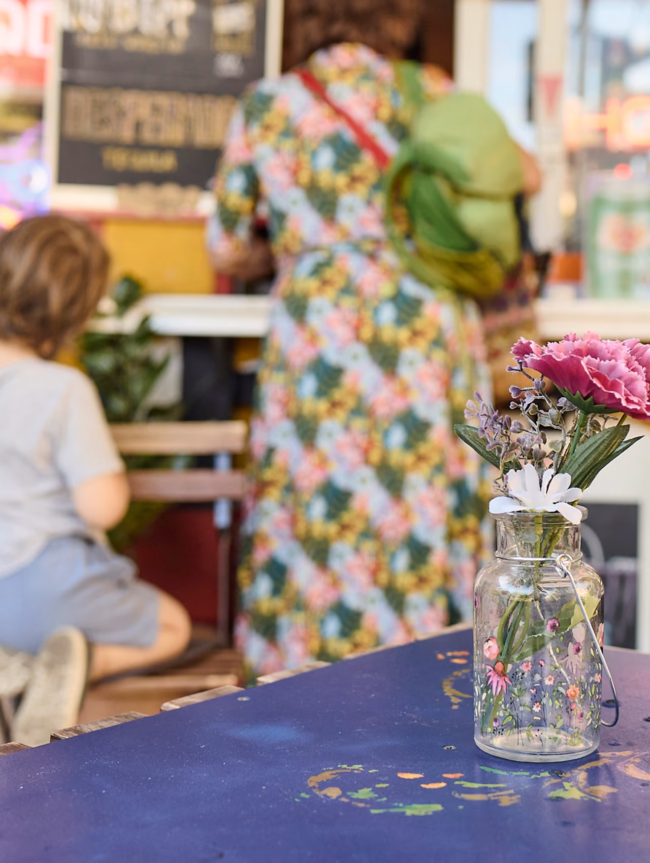 Gäste an einem Wasserhäuschen, auf dem Tisch eine Vase mit Blumen