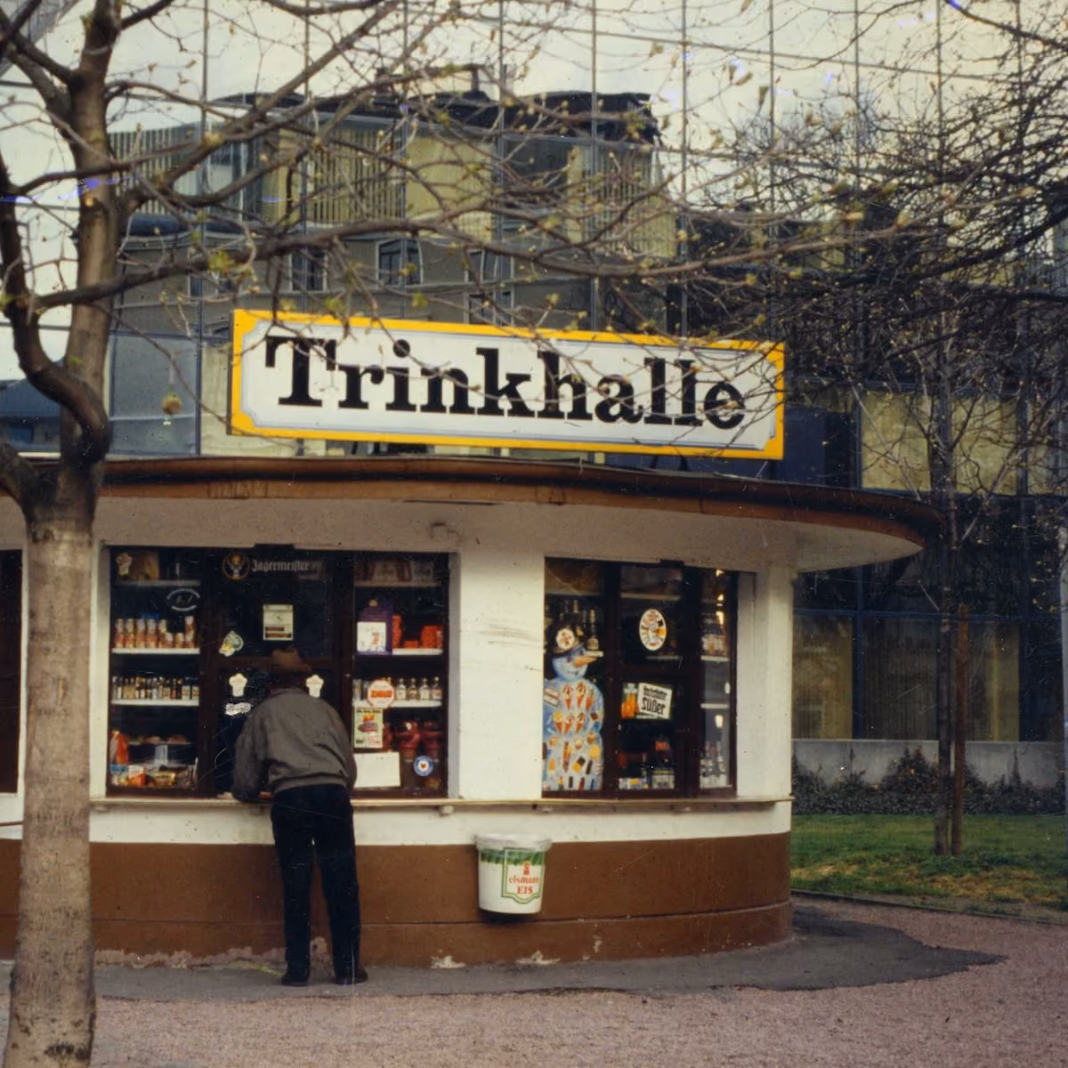 Wasserhäuschen mit Schild Trinkhalle, ein Kunde steht am Verkaufsfenster