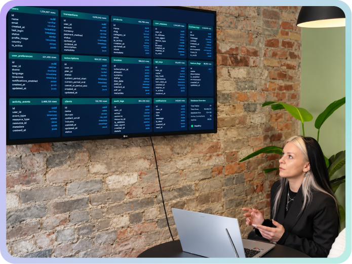 Woman in black blazer looking at screen displaying data charts on a brick wall in an office.