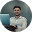 Cartoon man with a headset working on a laptop sitting at a desk with a smartphone nearby.