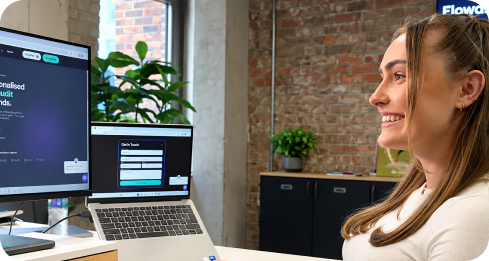 Woman smiling while working on a laptop and desktop with website audit software displayed.