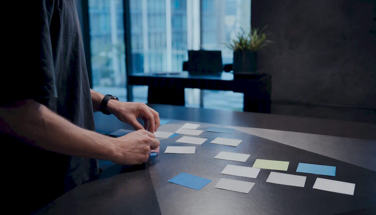 Hands organizing digital workflow cards on desk