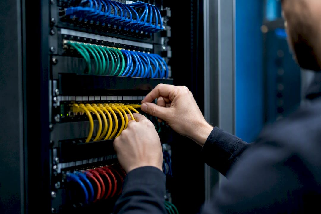Hands arranging network cables at patch panel