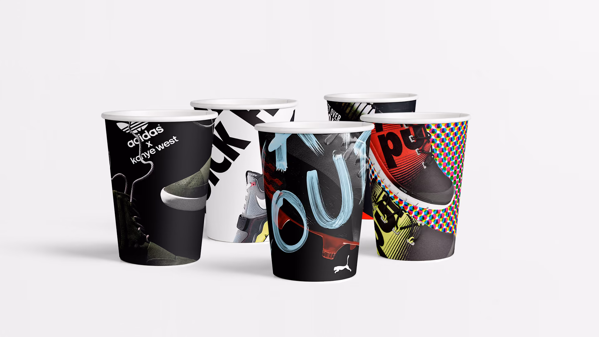 Five paper cups printed with trainer graphics and adidas and Puma logos, grouped on a white background