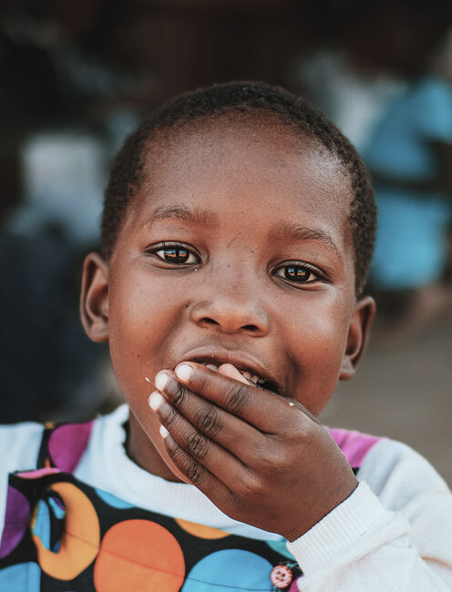 Close-up of a young child covering their mouth with hand