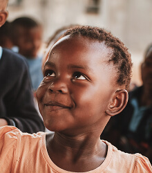 Smiling girl looking up outdoors near a group