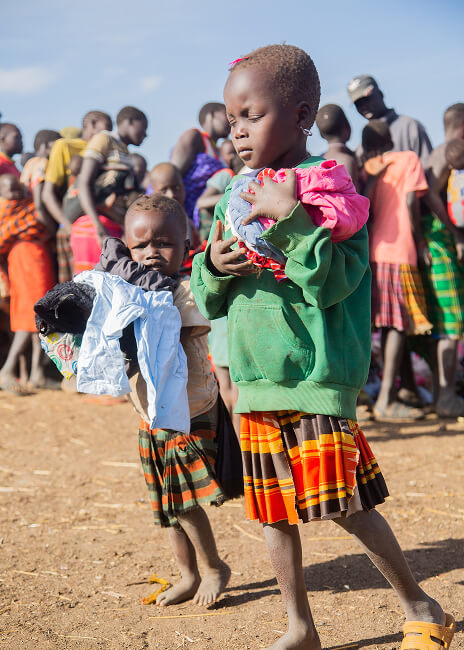 Children carrying donated clothing at a community distribution event