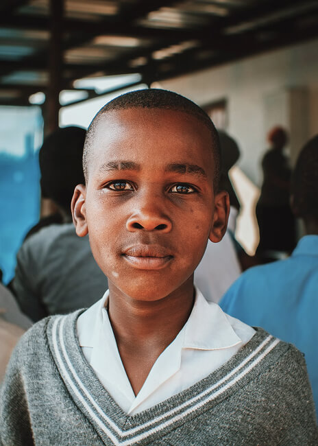 Boy in school uniform standing under a covered walkway