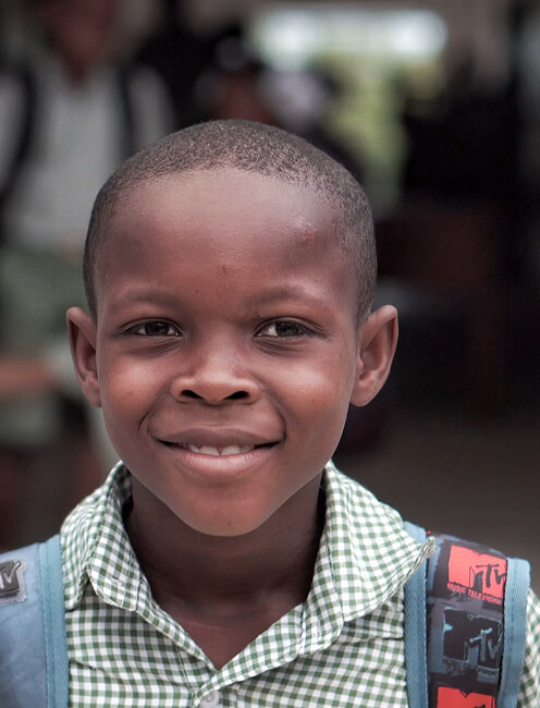 Smiling boy wearing a backpack in a checkered school shirt