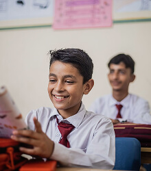 Boys in ties smiling in a classroom