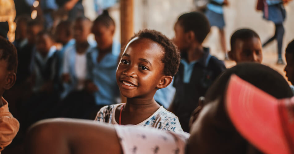 Smiling girl surrounded by classmates at a community gathering