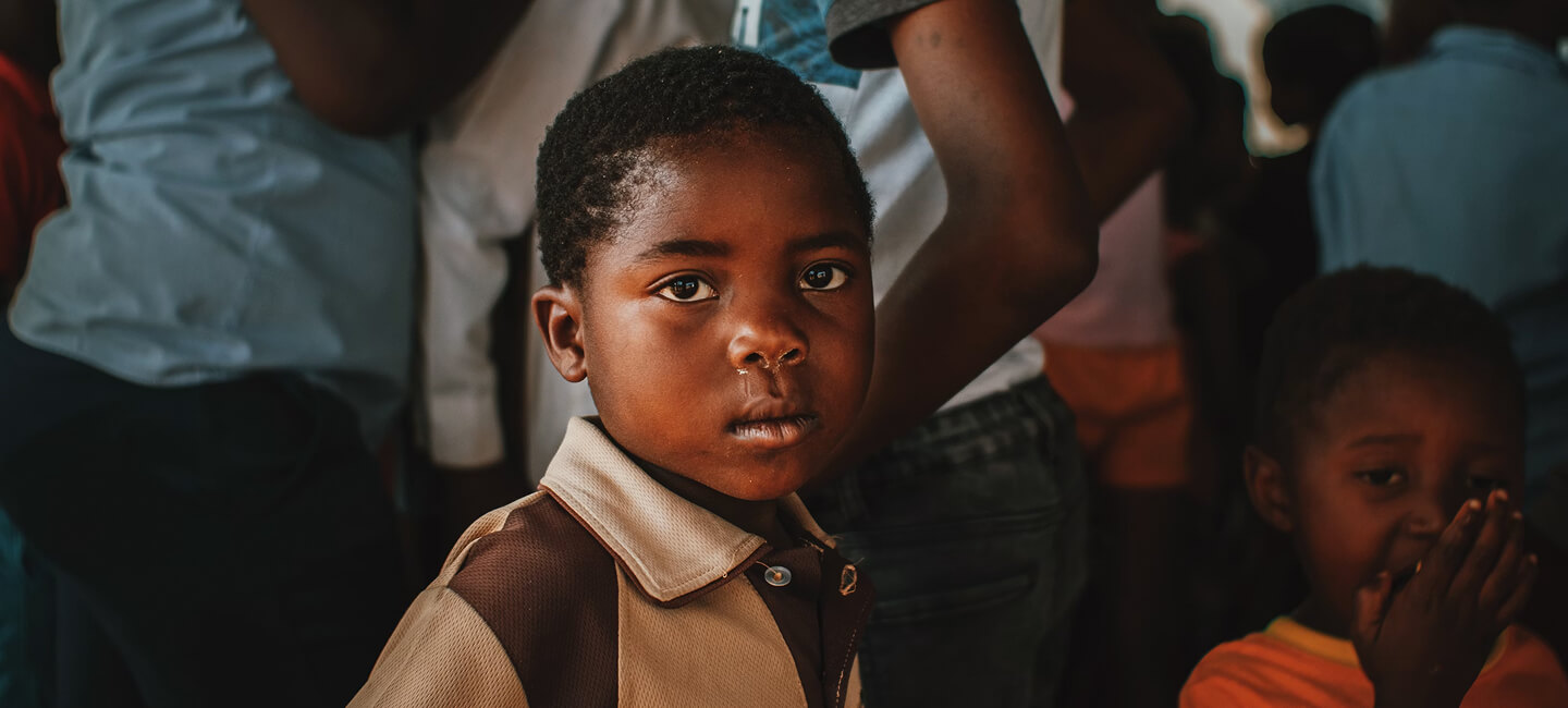 Young boy in school uniform waiting during a book distribution event