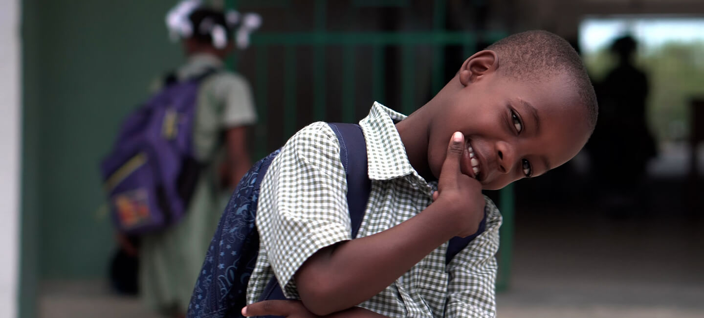 Smiling boy in school uniform with backpack after flood recovery