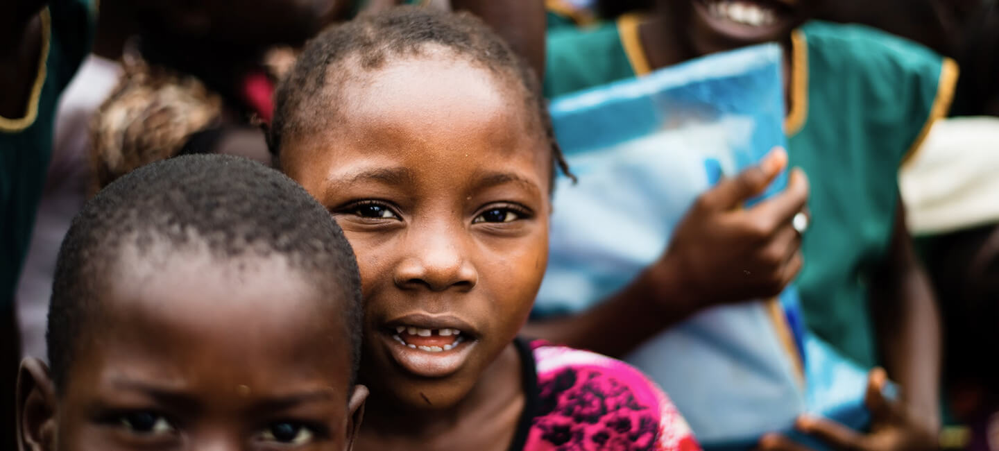 Close-up of a smiling child in a crowd, illustrating renewed hope for education