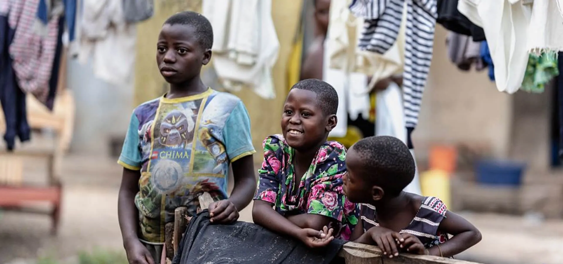 Children gathered outdoors near hanging laundry, representing Karuna's emergency health relief programs